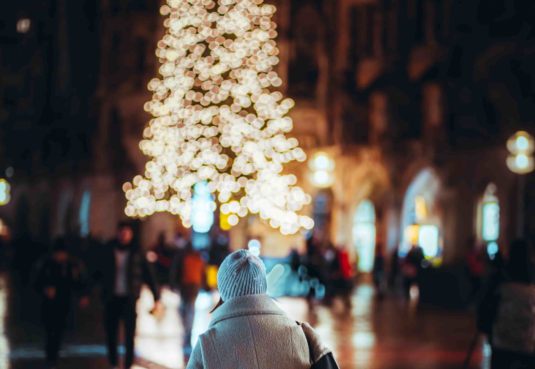 Chica en ciudad con luces navideñas.
